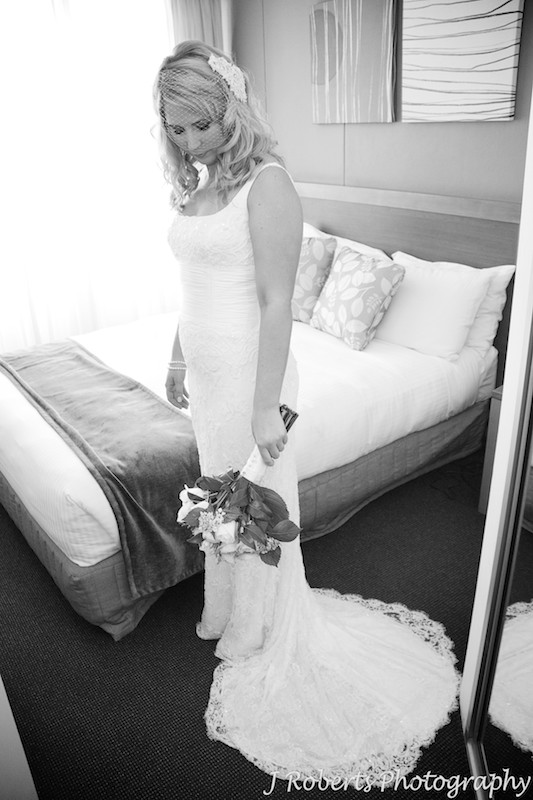 Bride looking down at her flowers in hotel room at Sebel Manly Beach - wedding photography sydney